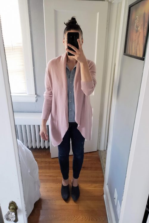 Woman taking selfie in mirror with pink cardigan, top, and jeans.