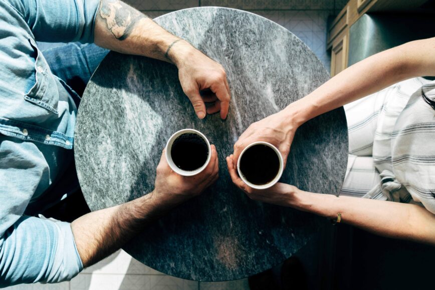couple holding coffee cups on table